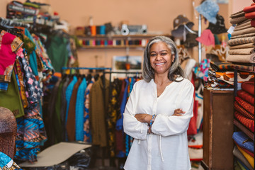 Mature woman smiling while standing in her fabric shop