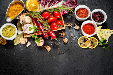 Different spices with raw and dry vegetables on black background. Top view. free space