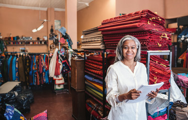 Smiling mature woman reading paperwork in her fabric shop 