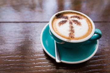 Cappuccino coffee with tree face on wooden table