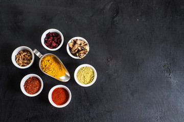 Different spices with raw and dry vegetables on black background. Top view. copy space