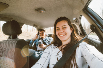 woman driving a car. man sitting at backseats as passenger