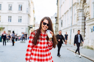 Fototapeta premium woman drinking cool drink while walking city street at summer day
