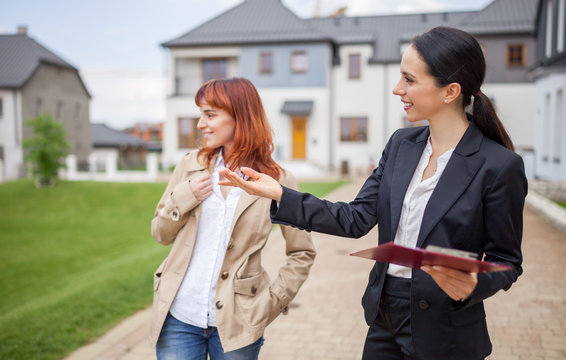 Young woman with real estate agent visiting house for sale in residential area