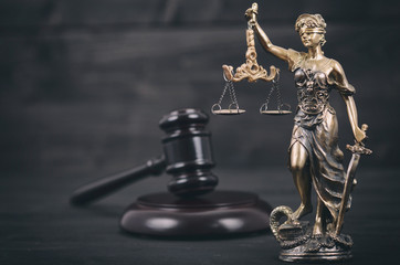 Scales of Justice, Judge Gavel, Justitia, Lady Justice on a black wooden background.