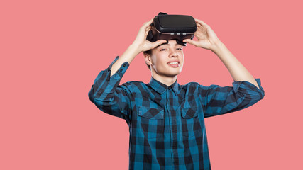 Young man with vr headset on pink background.