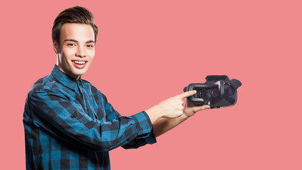 Young man with vr headset on pink background.