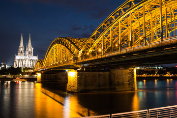 Fototapeta premium Kölner Dom beleuchtet mit Hohenzollernbrücke close up