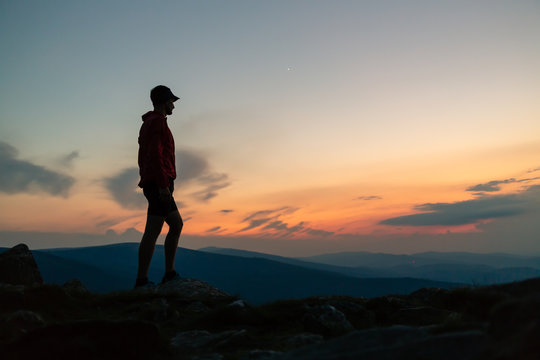 Man celebrating sunset looking at view in mountains