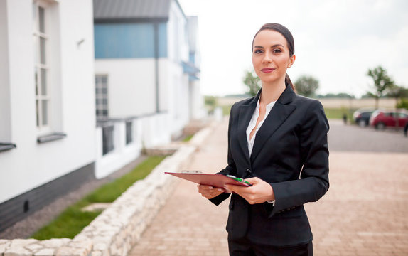 Real estate agent in front of house for sale ready to presenting offer, copy space