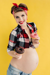 pregnant girl in pin-up style with two donut in hand