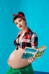 Pregnant girl on blue background in pin-up style