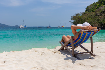 A girl in a white hat sunbathing in a deckchair and looking into