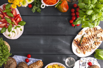 A lot of equal food on the table, Italian caprese salad, grilled fish, salad and flowers. A healthy and healthy lunch for the family. Copy space, above, flat lay