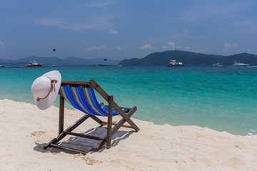The white hat lies on the edge of the chaise longue, the seashore with a beautiful view.