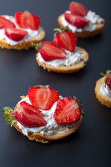  Fluffy buttermilk biscuits shortcake with red ripe strawberries and fresh whipped cream on a black background