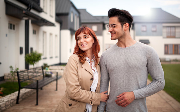 Happy couple walking at residential area in front of their new home