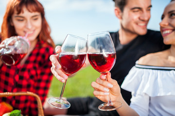 Group of happy young people having picnic and drinking, enjoying summer and having fun in nature
