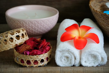 Fototapeta na wymiar White towels decorate with orange flower near dry aroma rose on spa set table.