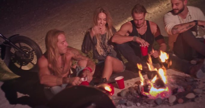 Rebel friends with motorcycles partying with alcohol around bonfire