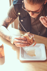 Portrait of a hungry hipster guy with a stylish haircut and beard sits at a table, decided to dine...