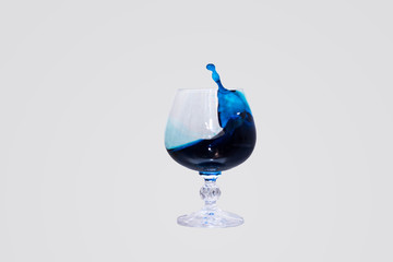 A glass in which a splash of blue liquid