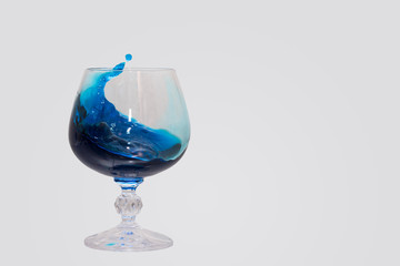 A glass in which a splash of blue liquid