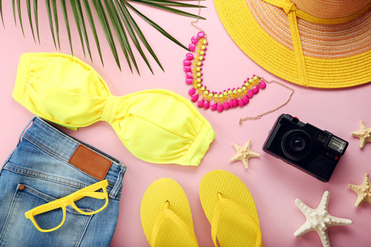Yellow swimsuit with jeans and green palm leaf on pink background