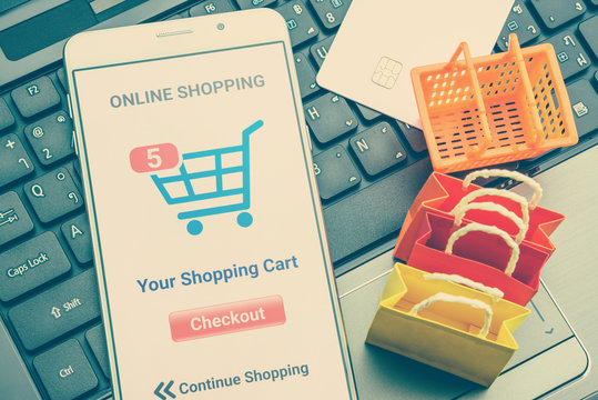 Online shopping / retail ecommerce and delivery service concept : Moblie with shopping app, a credit card on a laptop, depicts consumers purchase or order products from suppliers or digital stores.