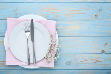 Kitchen cutlery with plate and gypsophila flowers on blue wooden table