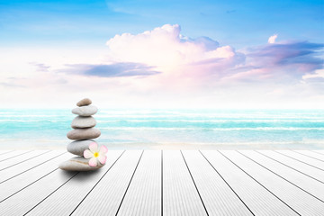 Stack of pebble stones and Plumeria at the beach on a wooden surface. Concept Zen, Spa, Summer, Beach, Sea, Relax.