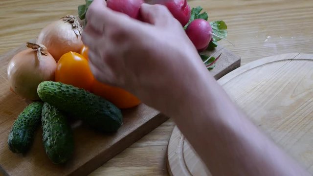 Man's hands cutting radish on a wooden cutting board