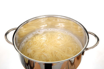 Gotowanie makaronu spagetti w błyszczącym metalowym garnku.