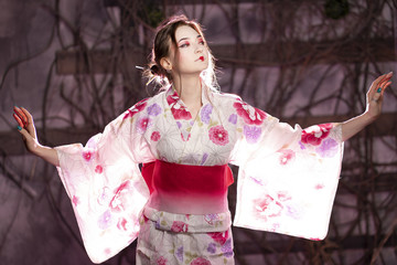 elegant girl in a classic traditional dress Japanese kimono white and pink standing alone on dark background in the studio