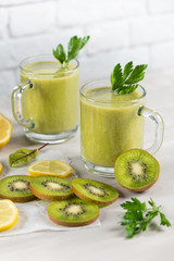 A freshly prepared smoothie of kiwi, lemon, orange and parsley  on a cement table. Diet vegetarian food. Raw foods