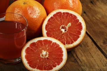 Grapefruit juice and fresh grapefruit on a wooden background. Fresh grapefruit juice in a glass bowl.