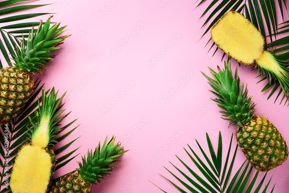 Wall mural half slice of fresh pineapple and whole fruit, palm leaves on yellow background. top view. copy spac