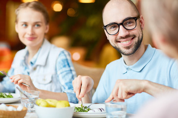 Crop view of smiling man spending time with friends and eating in restaurant