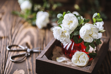 Bouquet of roses in a vase on wooden rustic background. Flower composition 