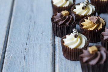 Cupcakes decorated with chocolate,caramel and vanilla icing on a wooden background