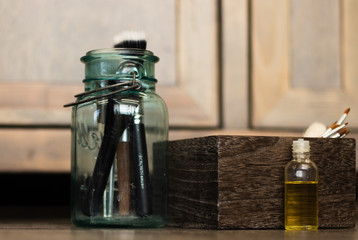 Obraz na płótnie Canvas Brushes in a jar next to a wood box and jojoba oil