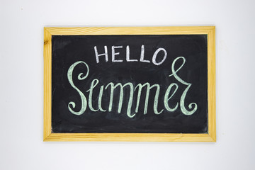 Obraz premium Hello Summer inscription by chalk on blackboard top view photo. Hello Summer handdrawn illustration on chalkboard.