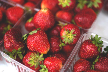 Fresh and juicy and delicious organic farm strawberries in small baskets for sale at the farmers market. Raw sweet food. Close up.