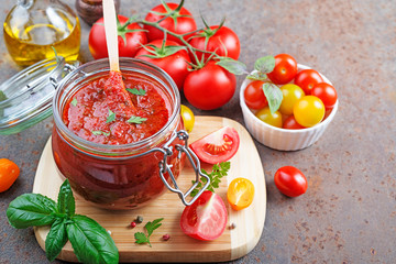 Tomato sauce in a glass jar and ingredients.