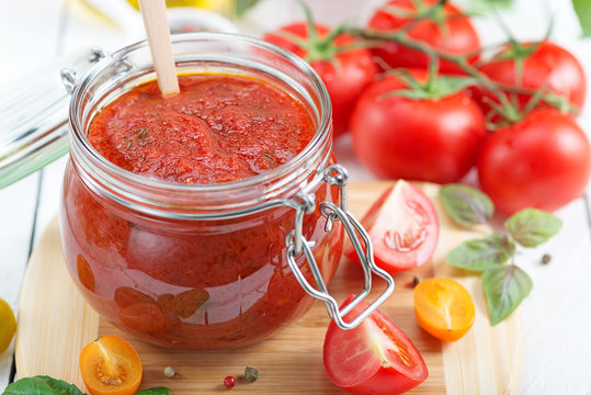 Tomato sauce in a glass jar and ingredients.
