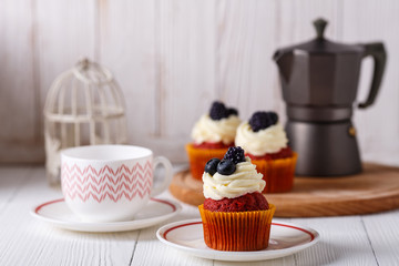 Tasty red velvet cupcakes on wooden table. Geyser coffee maker.