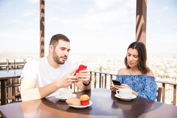Beautiful young couple using smartphone during breakfast time