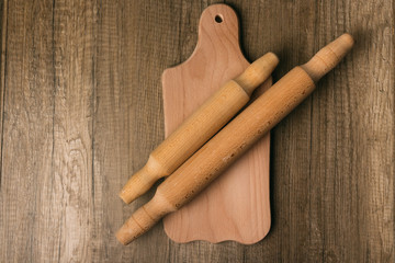 on the cutting board lies two wooden rolling dough-rolls