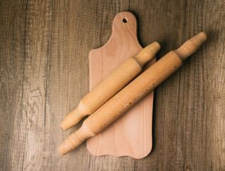 on the cutting board lies two wooden rolling dough-rolls