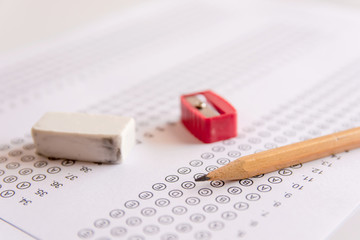 Pencil, Sharpener and eraser on answer sheets or Standardized test form with answers bubbled. multiple choice answer sheet